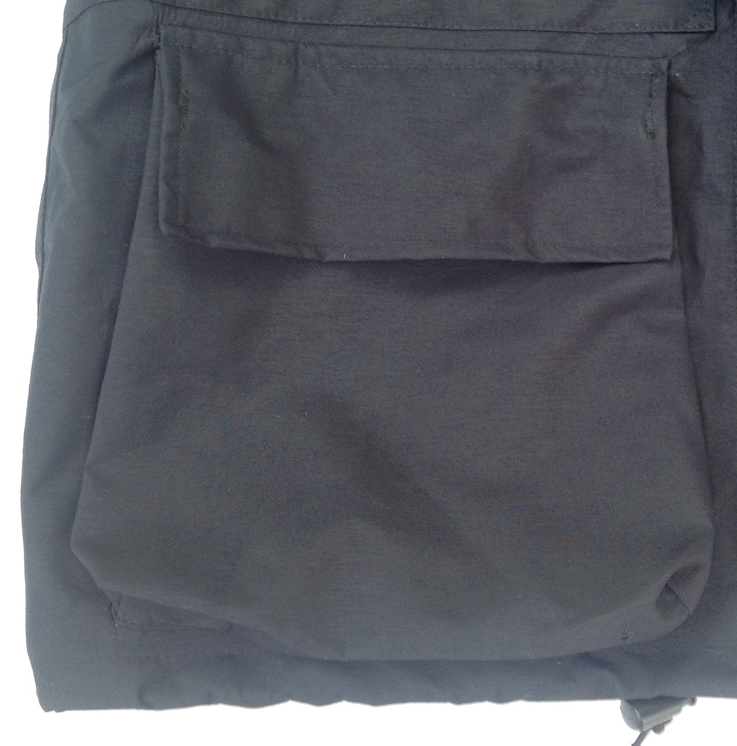 La veste dispose de deux grandes poches plaquées situées sur la partie basse, avec rabats supérieurs fermés par velcro.